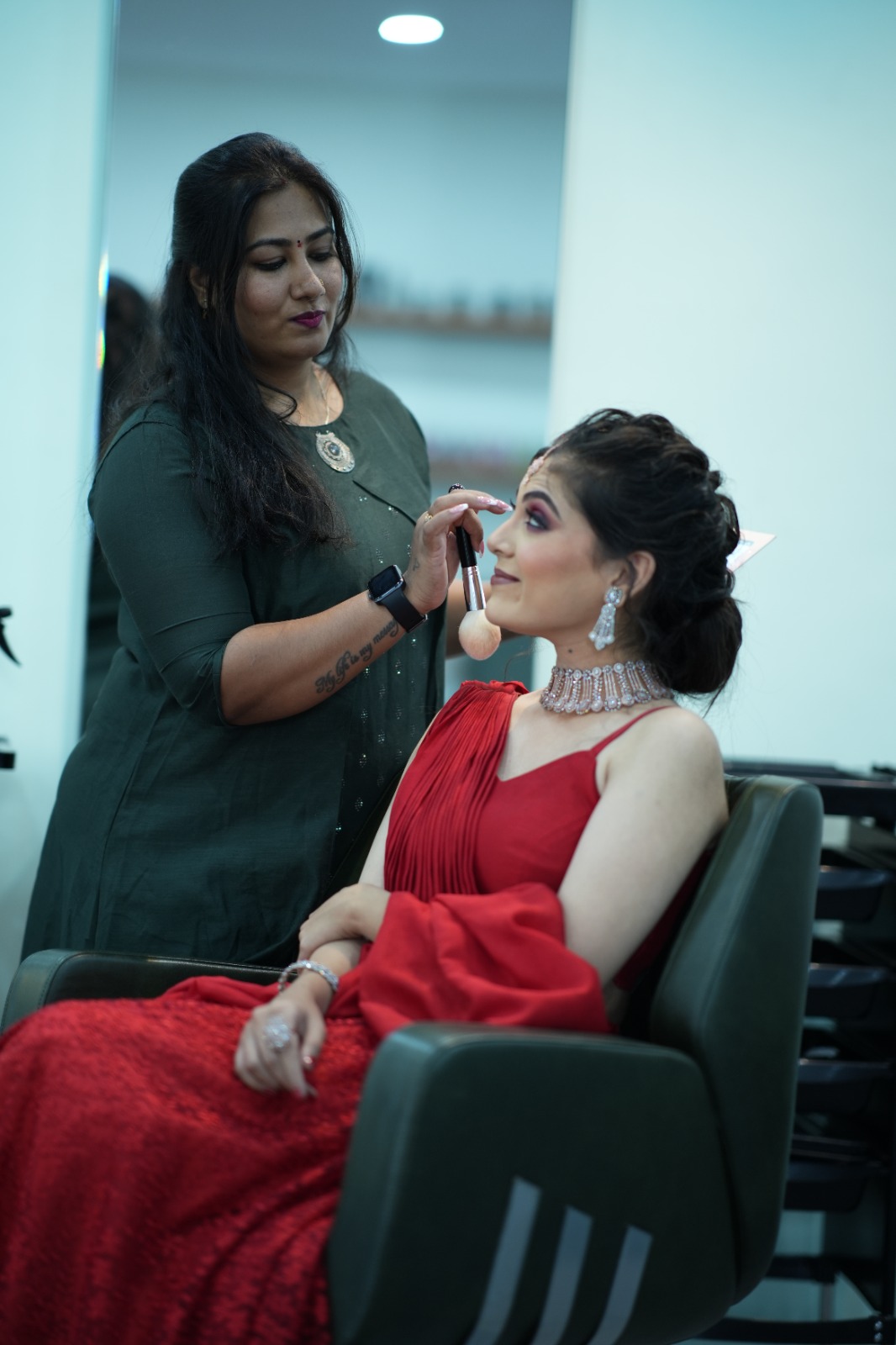 Ranjitha applying makeup to client in red dress